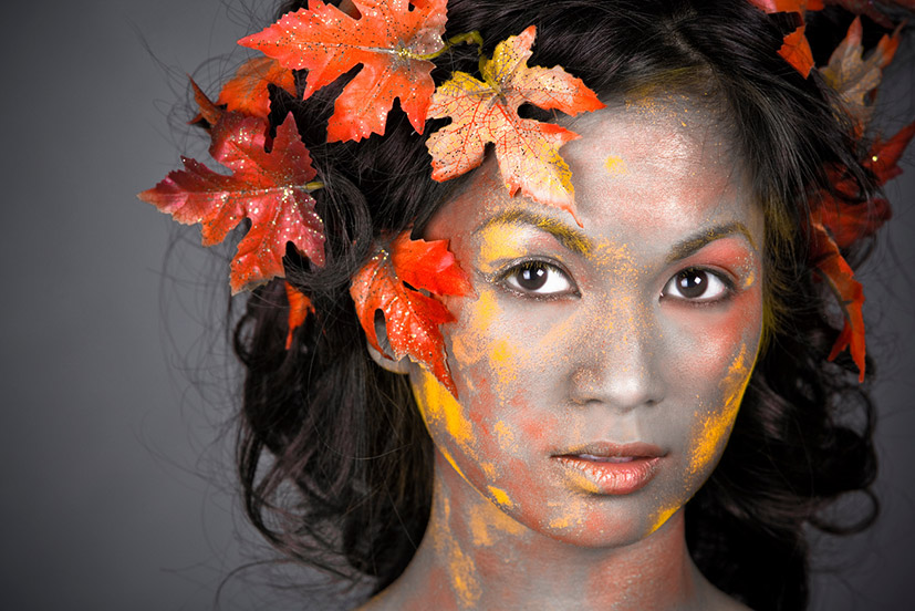 Frau mit Herbstblättern im Gesicht